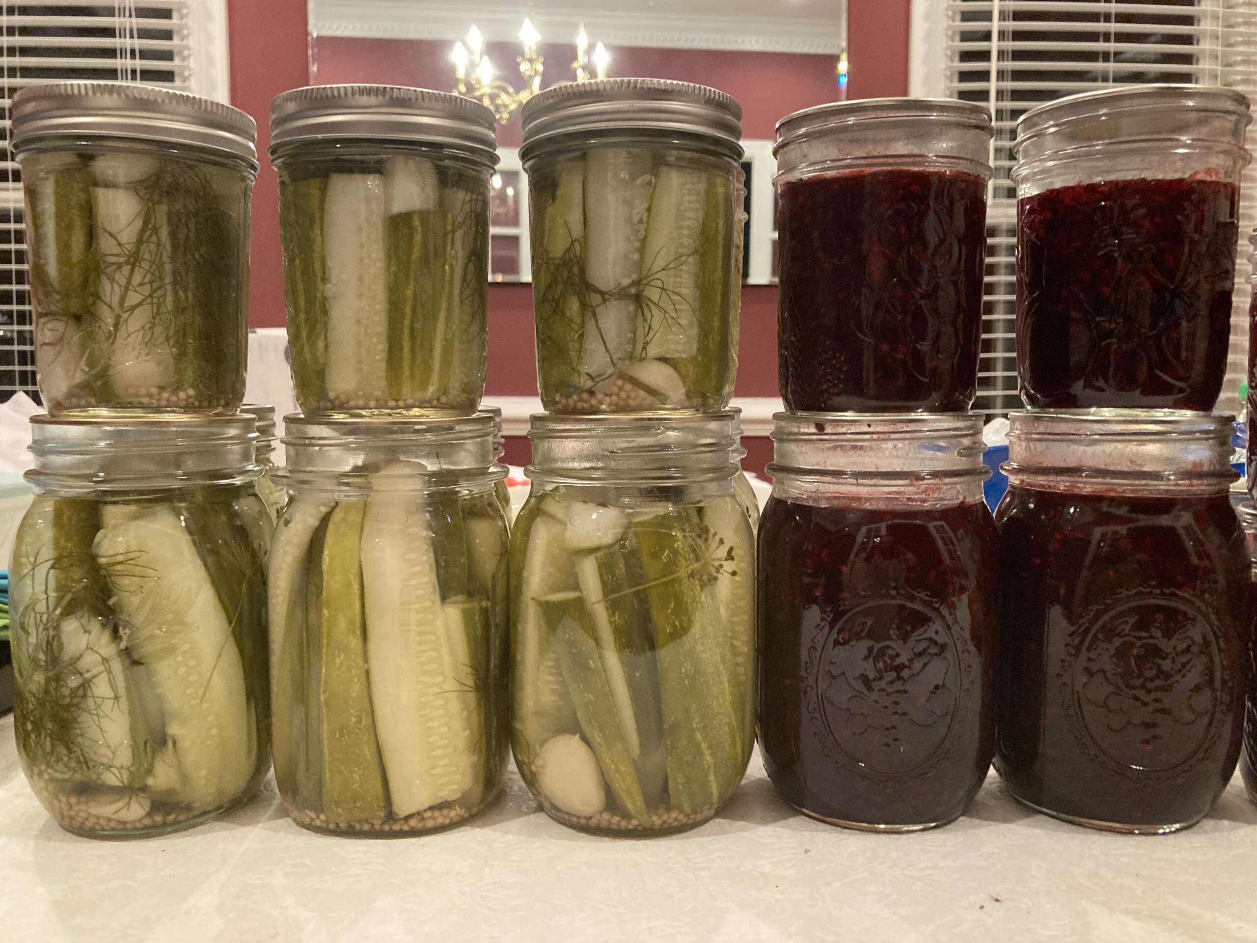 Homemade dill pickle and blackberry jam in glass jars