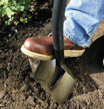 A boot pushing a shovel into the ground
