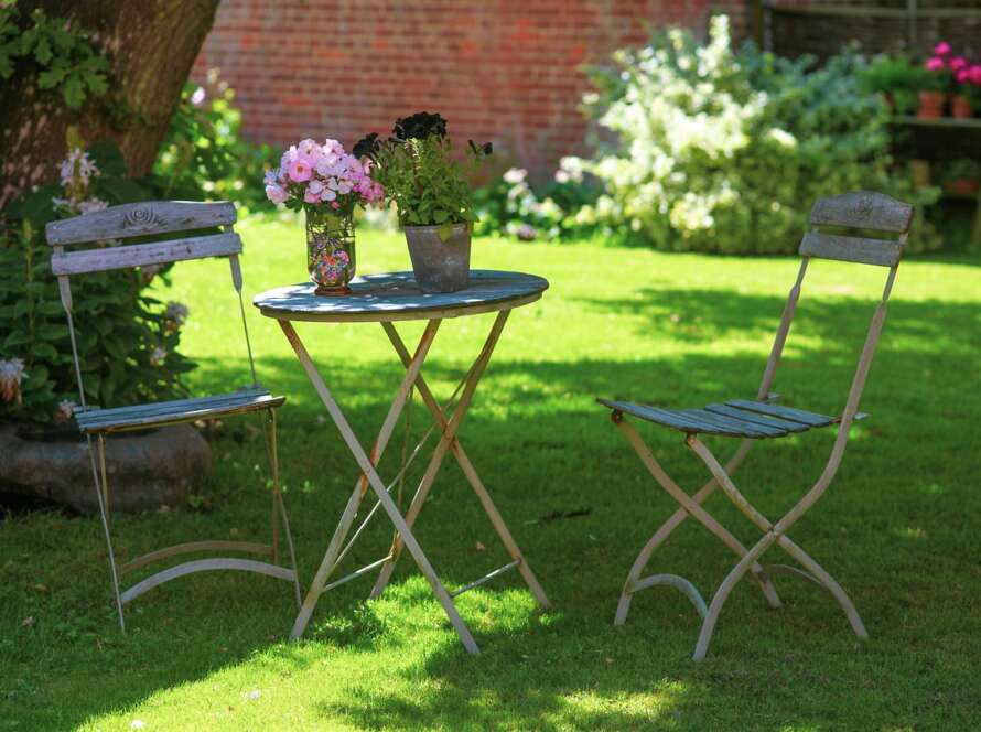 A table and chair set up in the shade of a tree